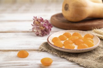 Jelly pumpkin candies on white wooden background and linen textile. selective focus, close up, side