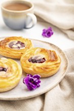 Small cheesecakes with jam and almonds with cup of coffee on a white concrete background and linen