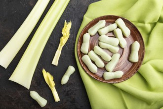 Jelly celery candies on black concrete background and green linen textile. close up, top view, flat