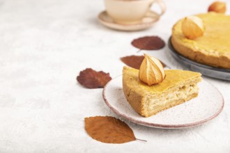 Autumn onion pie decorated with leaves and cup of coffee on gray concrete background. Side view,