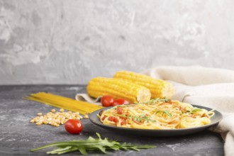 Corn noodles with tomato sauce and arugula on a black concrete background and linen textile. Side