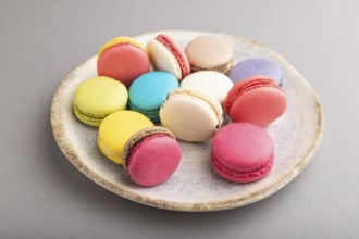 Multicolored macaroons on ceramic plate on gray pastel background. side view, close up, still life.