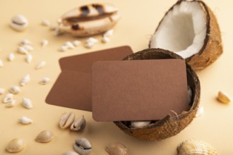 Brown paper business card with coconut and seashells on orange pastel background. Side view, copy