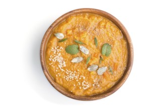 Sweet potato or batata cream soup with sesame seeds in a wooden bowl isolated on a white background