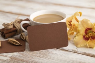 Brown paper business card mockup with orange day-lily flower and cup of coffee on white wooden