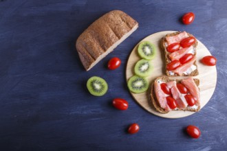 Smoked salmon sandwiches with butter on dark wooden background. cherry tomatoes. top view, copy