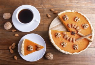 Traditional american sweet pumpkin pie decorated with nuts, on brown wooden background. cup of