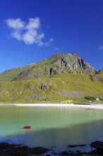 Fine, crystal-clear sandy beach with turquoise-green water and a red boat, high mountains, Haukland