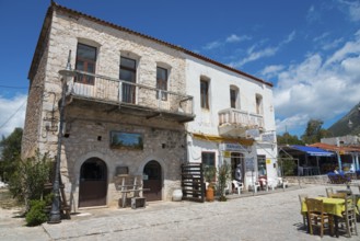 Stone building with restaurant terrace under a clear blue sky and a mountain in the background, Old