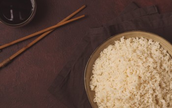 A plate of boiled rice, with wooden sticks, on a brown background, no people, selective focus,