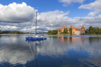 Blue yacht on Galve lake, Lithuania with Trakai castle and cloudy sky on background