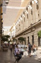 Fabric spread over buildings to provide shade in busy shopping street called Velazquez in central