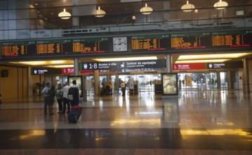 Passengers looking at display board information inside, Maria Zambrano railway station, Malaga,