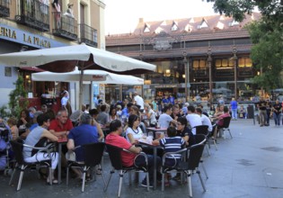 People sitting at street cafe nearby Mercado de San Miguel market, Madrid city centre, Spain,