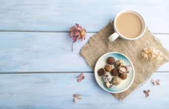 Chocolate truffle candies with cup of coffee on a blue wooden background and linen textile. top