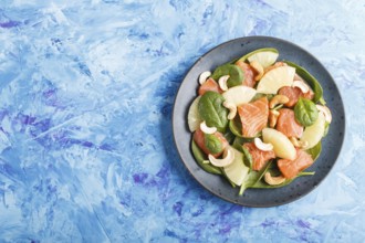 Fresh salmon with pineapple, spinach and cashew on a blue concrete background. Top view, copy