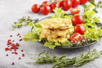 Minced chicken cutlets with lettuce, tomatoes and herbs on a gray concrete background. side view,