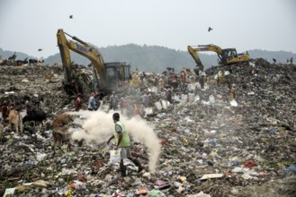 Municipality workers working with excavator as rag pickers searches for recyclable materials next