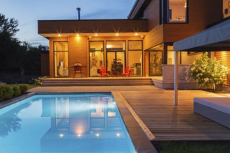 Rear of modern cube style home with stained horizontal wood cladding, in-ground swimming pool and