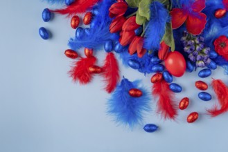 Blue and red arrangement of tulips, feathers and Easter eggs on a light blue background