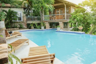 A crystal clear swimming pool surrounded by trees. Concept of home swimming pool designs, Beautiful