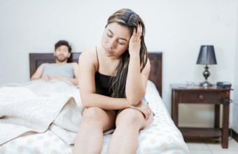 Wife on the edge of the bed arguing with her husband. Upset woman arguing with her husband in bed.