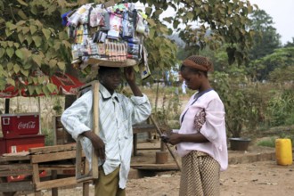 Black woman buying goods from man carrying merchandise on his head in Bamako, Mali, West Africa,