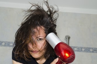 Portrait of a Beautiful Woman Drying Her Hair with a Hair Dryer in Bathroom in Switzerland