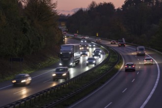 Evening scene on a motorway with heavy traffic, illuminated by headlights under a twilight sky,