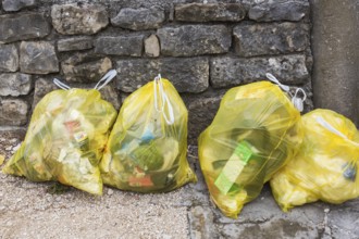 Close-up of translucent yellow plastic thrash bags filled with various discarded domestic garbage,