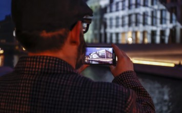 A man takes a photo of the Humboldt Forum with a smartphone during the Festival of Lights, Berlin,