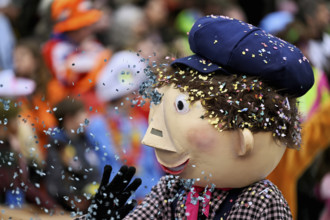 Person masked as a little boy with confetti in his hair at the carnival parade of the Wey guild on