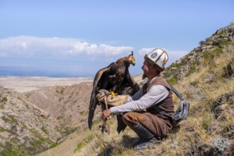 Traditional Kyrgyz eagle hunter with eagle in the mountains, near Kysyl-Suu, Kyrgyzstan, Asia