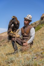 Traditional Kyrgyz eagle hunter with eagle in the mountains, near Kysyl-Suu, Kyrgyzstan, Asia