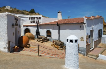 A traditional Spanish village with white buildings and clay jars under bright sunshine, Cueva del