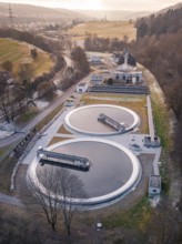 Aerial view of a sewage treatment plant focussing on the round clarifiers next to a forest, Nagold,