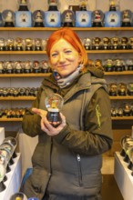 Saleswoman presenting a snow globe in a stand for snow globes at the Christmas market at St