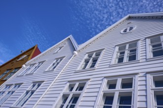 Traditional wooden houses under a blue sky with pitched roofs and multiple windows in a sunny old