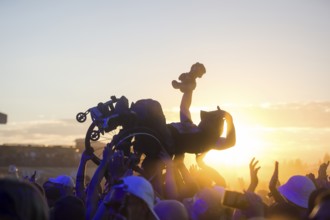 A wheelchair user crowdsurfing in front of sunset at the Highfield Festival on Friday, Störmthaler