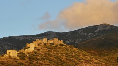 Sunset illuminates the historic buildings and the hilly landscape, Vathia, residential tower