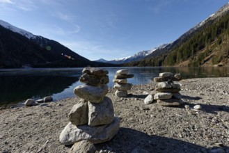 Cairns in winter on the icy lake, Lake Antholz in the Antholz Valley, Val Pusteria, South Tyrol,