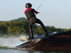 Young man with wakeboard on obstacle, water sports, water skiing in wakepark