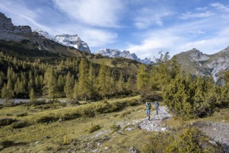 Two mountaineers on a hiking trail, mountain panorama with rocky steep peaks, yellow-coloured