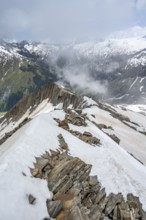 Mountaineer on a rocky ridge with snow, descent from the summit of Schönbichler Horn, view of