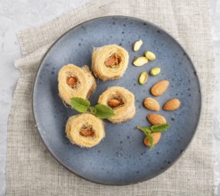 Kunafa, traditional arabic sweets in blue ceramic plate on a gray concrete background. top view,