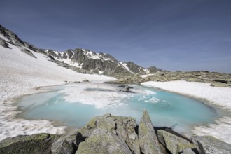 Frozen meltwater lake with snow-covered mountains in the background, Neukirchen am Großvenediger,