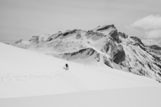 Lone ski tourer in snowy mountain landscape, mountain peak Sex des Molettes in the background,