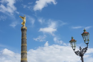 Victory Column next to a beautiful, old street lamp in a blue sky with white clouds, towering