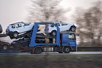 Truck, lorry, articulated lorry with new Dacia cars driving fast on the A92 motorway, motion blur,