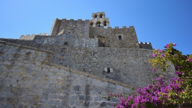 Historic castle walls with blooming flowers and clear blue sky, Agiou Theologou Monastery, St